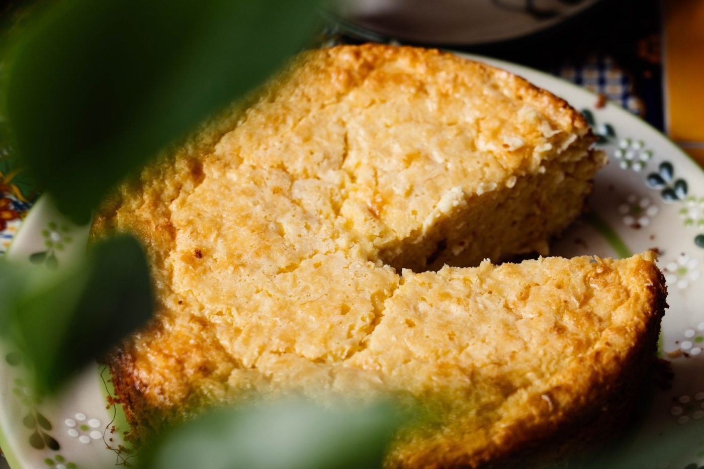 A square baking pan with golden gluten free cornbread cooling on a kitchen counter next to a wire rack.