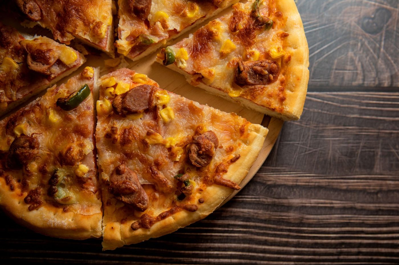 A slice of savory gluten free cornbread studded with jalapeño slices and shredded cheese on a wooden cutting board.