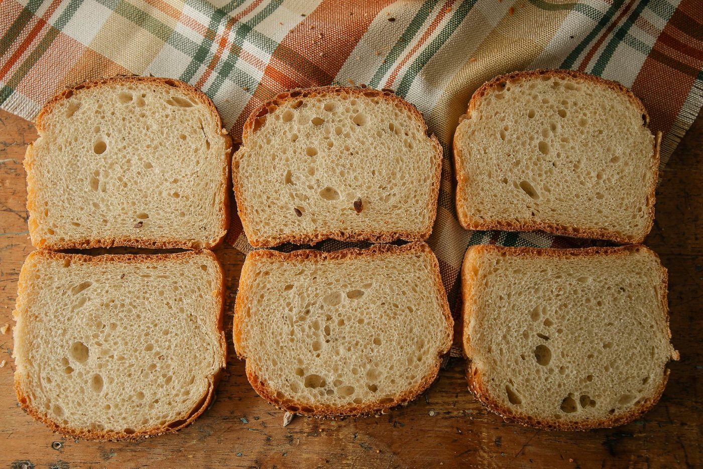 A gluten free bread loaf that has collapsed in the middle, sitting on a kitchen counter.