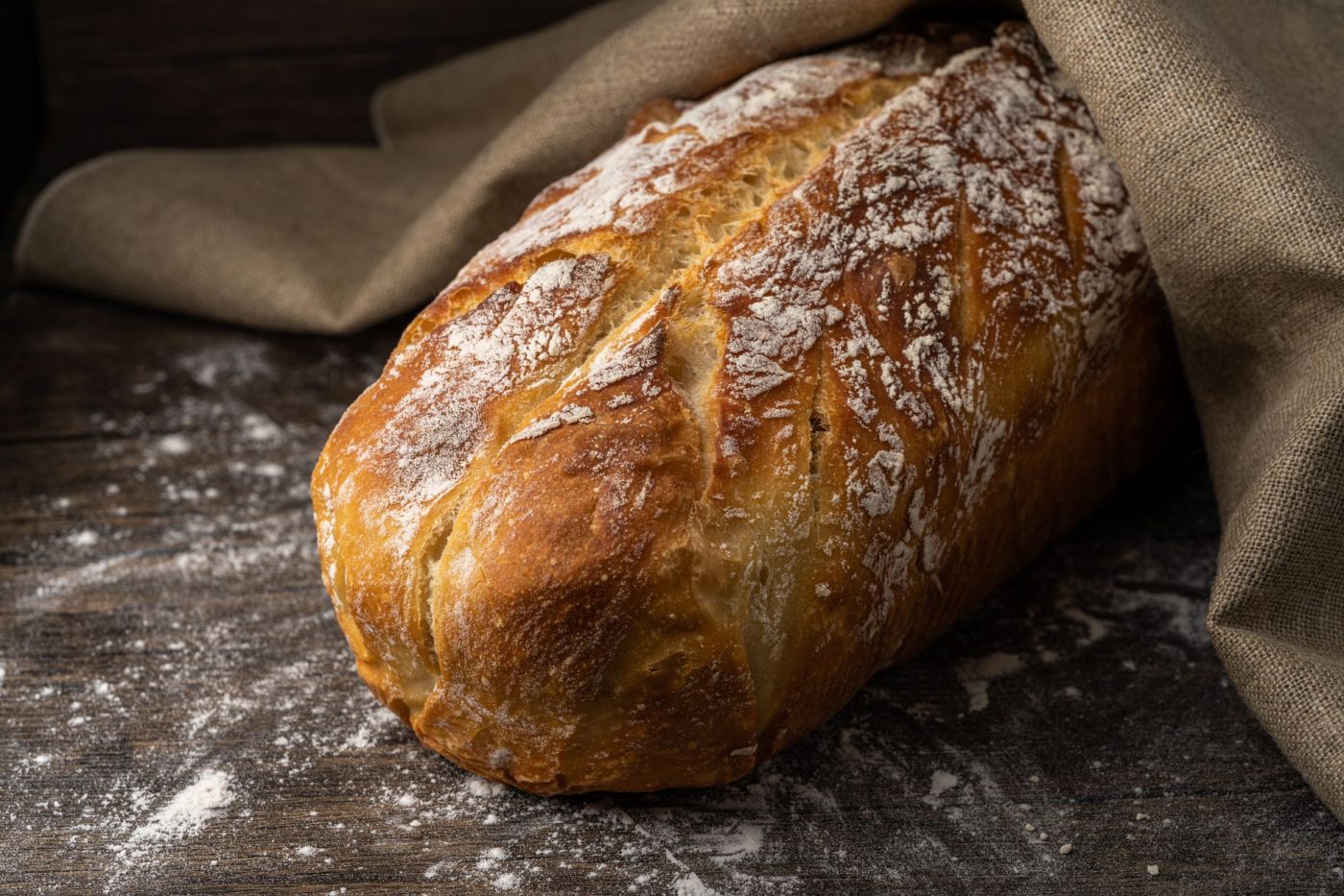 A bowl of gluten free bread dough covered with plastic wrap resting inside a refrigerator.