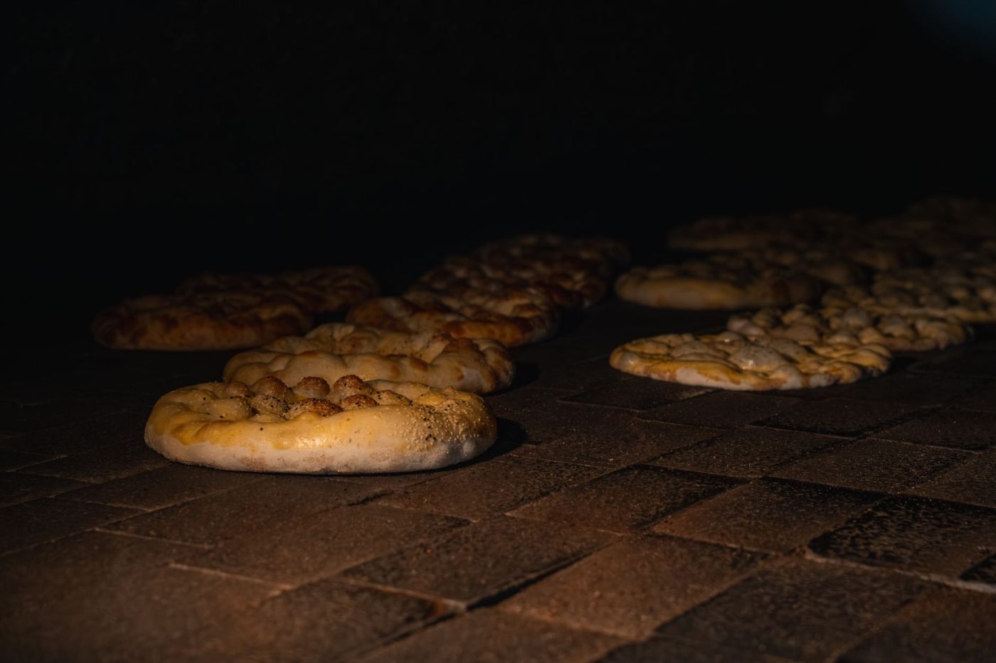 A stack of freshly cooked gluten free naan breads with blistered bubbles on a plate in a cozy kitchen setting.